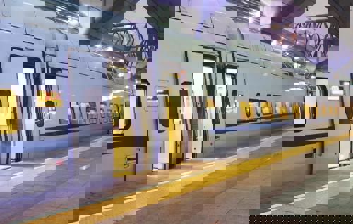 A train standing at a platform in the evening, lights on and doors open.