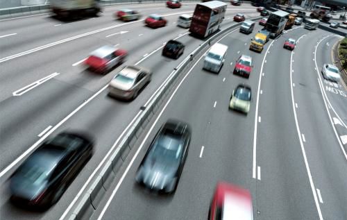 Cars moving very fast across 8 lanes of a motorway, most are blurred.