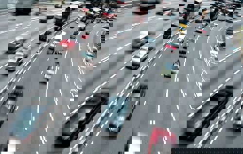 Cars moving very fast across 8 lanes of a motorway, most are blurred.
